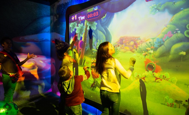 Kids playing together with an interactive wall-sized digital game at the Critter Creek
